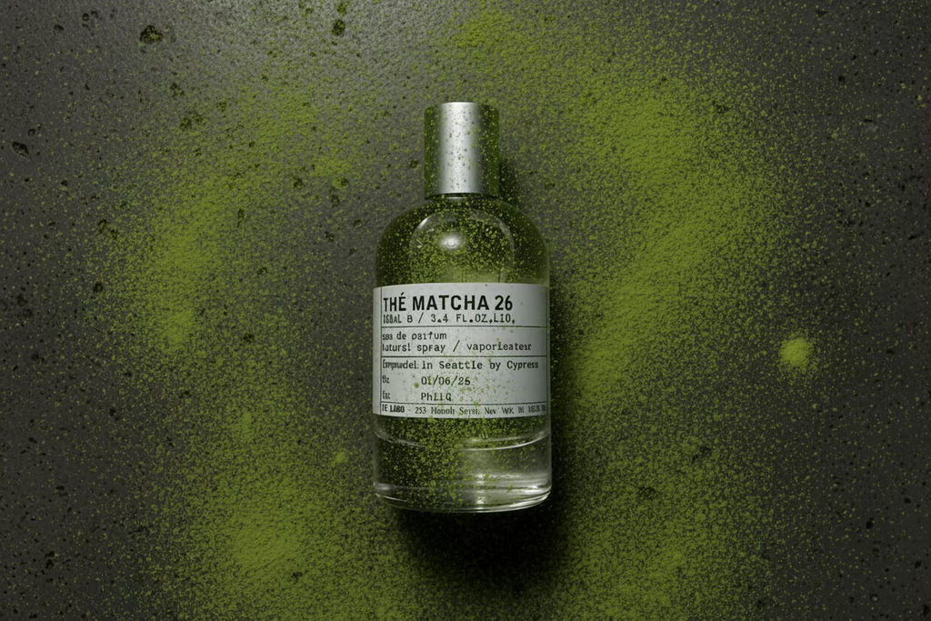 Perfume bottle labeled 'The Matcha 26' on a wooden surface